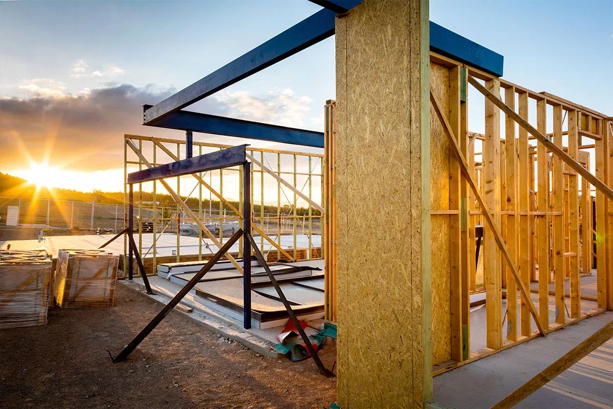 Timber wall frames and steel beams on a residential build at sunset
